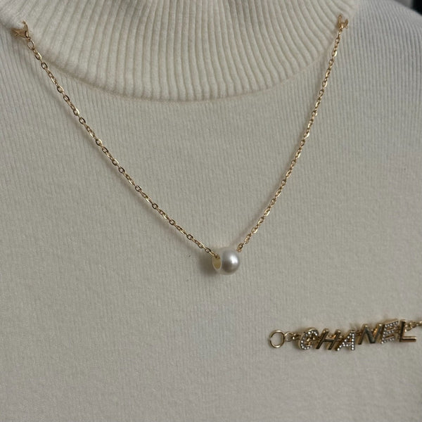 Top en maille à manches longues avec pompon et collier doré en métal siglé Chanel