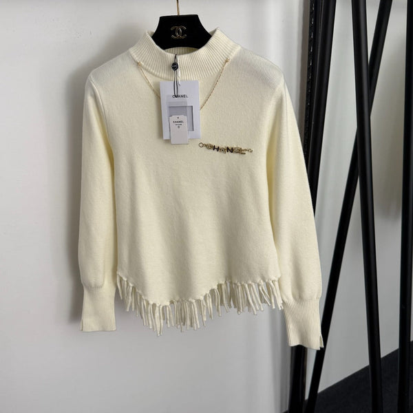 Top en maille à manches longues avec pompon et collier doré en métal siglé Chanel