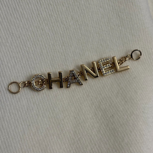 Top en maille à manches longues avec pompon et collier doré en métal siglé Chanel