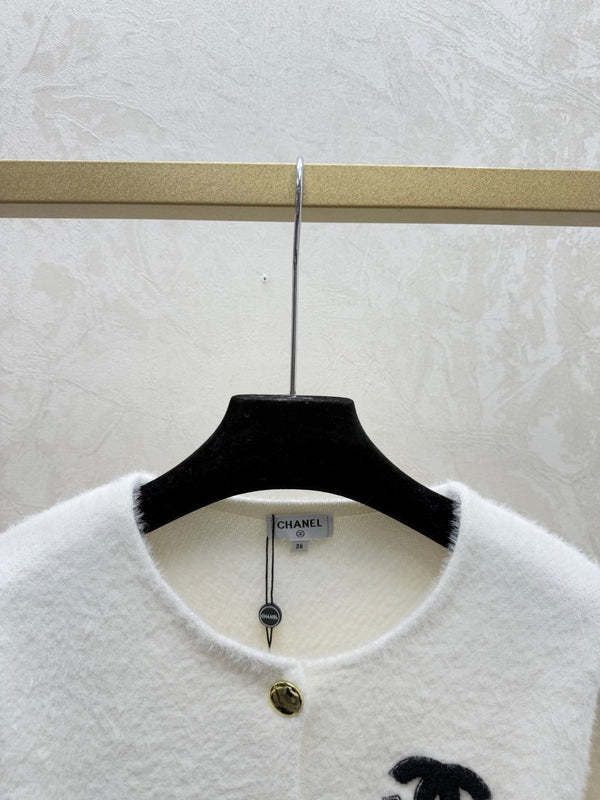 Cardigan Chanel 2025 en laine blanche et noire bordé de fausse fourrure